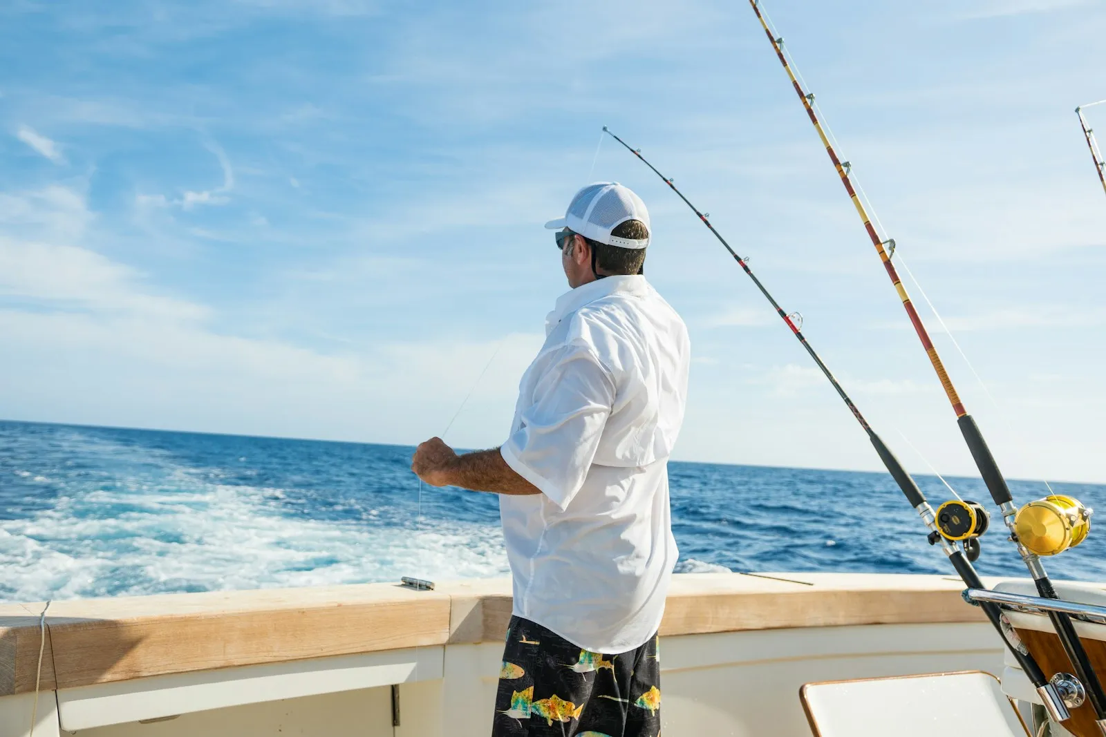 Un pescador junto a cañas de trolling en un barco de pesca deportiva