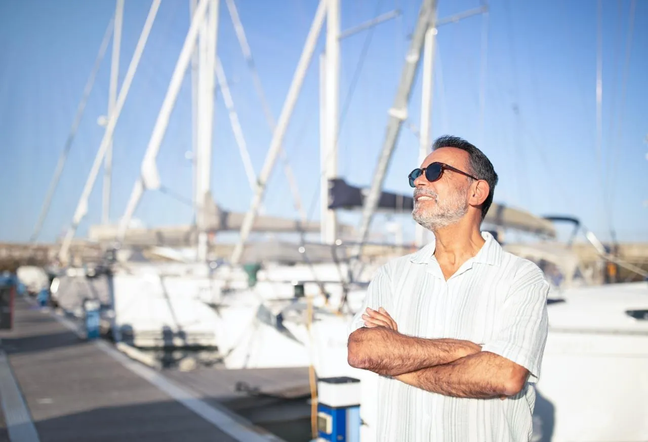 Un empresario seguro de sí mismo, con los brazos cruzados, mirando una marina